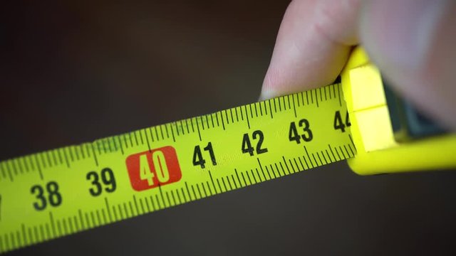 Macro of Hands Using a Yellow Tape Measure