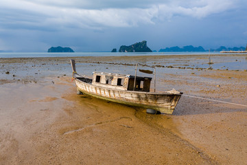 Low aerial view of an old wooden boat stranded at low tide at dusk on a beautiful tropical island