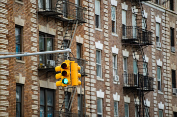 Close-up view of a traffic light and some buildings on background with windows and emergency stairs. Bronx District, New York, USA.