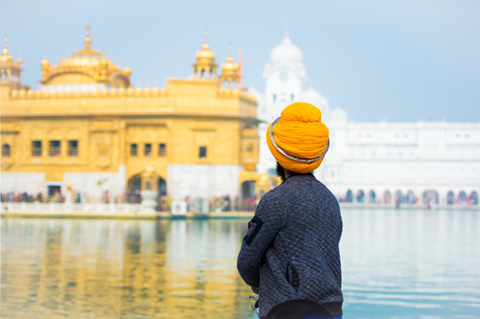 A Sikh religious is admiring the majestic Golden Temple of Amritsar in the state of Punjab, India.