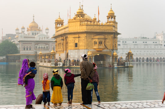 An indian family is admiring the majestic Golden Temple of Amritsar in the state of Punjab, India.