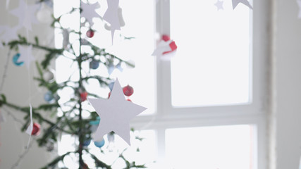 Paper stars hanging for background of a Christmas interior by the fir-tree next to the window. Christmas concept
