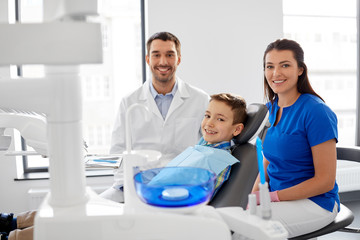 medicine, dentistry and healthcare concept - happy dentist, assistant and kid patient at dental...
