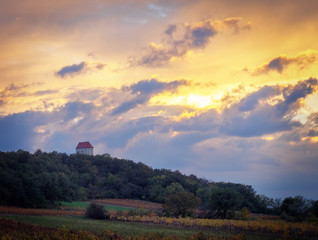 Naklejka na ściany i meble Small chapel between vineyards at sunset with dramatic clouds