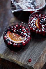 high angle view of glasses of homemade mulled wine with cranberries and oranges on wooden stand in kitchen