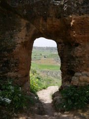 View of a rural landscape through an old red stone gate in the mountains of Ronda