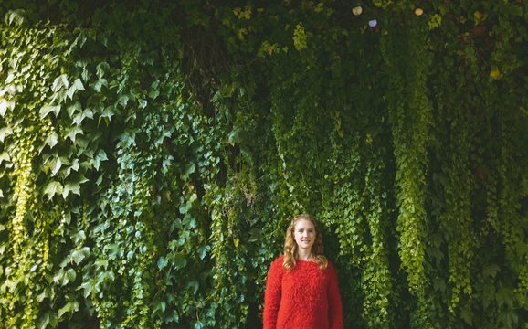 Woman standing against plant creeper in outdoor cafe
