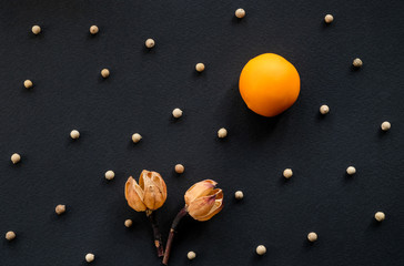 Image from an orange candy and dried flowers on a black background