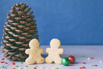 Big pine cone, gingerbread men and gifts on blue background. Happy New Year and Merry Christmas concept. Copy space