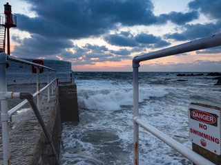 Steps into the sea on the end of Banjo Pier with a No Swimming sign at sunrise.