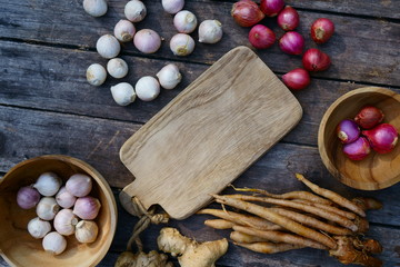 Top view of wooden table full of herbal vegetable ingredients, garlic, red onion, finger root, ginger, copy space