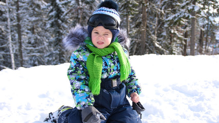 Fototapeta na wymiar A small child walks in the winter Park. Playing and smiling baby on white fluffy snow. Active rest and games.