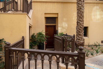 Arabic style townhouse villa in Dubai. Vintage door and fence with sand colored walls. Housing in UAE.