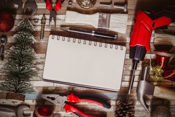 Merry christmas and Happy New year Craftsman Workspace background concept, Variety of handy DIY tools with Christmas ornament decoration. Top view with blank space notebook for your text.