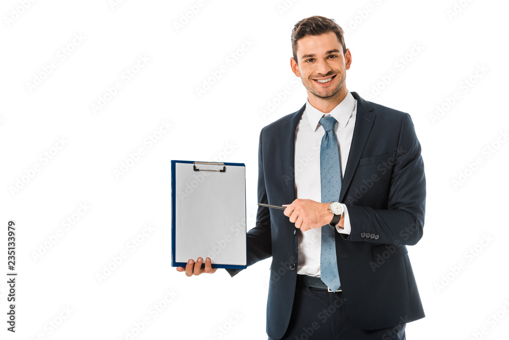 Wall mural smiling businessman in suit pointing at empty clipboard isolated on white