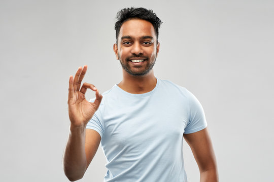 gesture and people concept - happy indian man in t-shirt showing ok hand sign over grey background