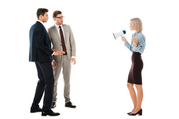 dissatisfied businesswoman speaking in megaphone and looking at colleagues isolated on white