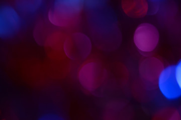 Bokeh. Holiday background. Christmas lights. Glitter. Defocused sparkles. New Year backdrop. Festive wallpaper. Blinks. Carnival. Bokeh retro style photo. Violet. Red. Blue.