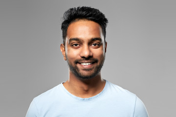 Fototapeta premium people concept - smiling young indian man over grey background