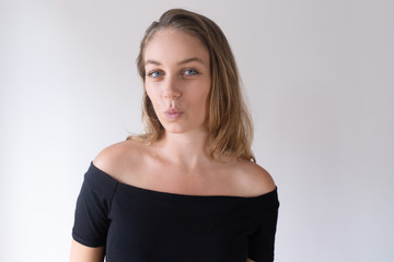 Obraz premium Portrait of beautiful Caucasian girl pursing lips for kiss. Young female student in black dress flirting with boyfriend. Dating concept