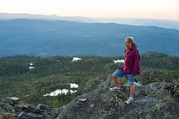 Portrait of man standing on the top of rock. watching sunset above mountain. Traveler exploring Scandinavia. Beautiful view of pink sky, Norway, Kongsberg