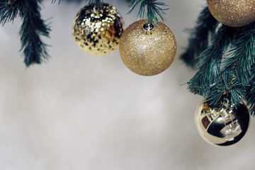 Shiny gold christmas balls on white with pine tree