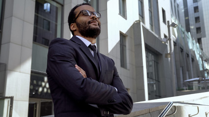 African office worker standing near modern office building, getting promotion