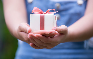 Woman hands holding present box with red bow