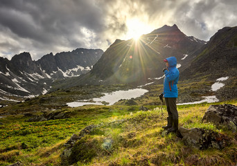 Pass hopping. Woman stands on mound in mountain tundra on cold morning