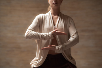 Calm young lady meditating and putting hands at the level of the stomach while practicing chi gong
