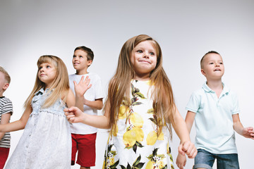 Group of fashion cute preschooler kids friends posing together and looking at camera on a white studio background. The friendship, fashion, summer concept. Space for text.