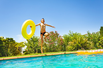 Happy boy with swim ring jumping in swimming pool