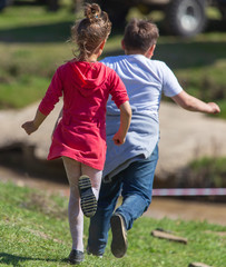 Girl and boy run on the green grass in nature