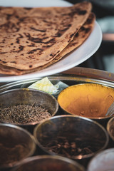A round container for spices - with ginger and roti - cooking Indian food. 