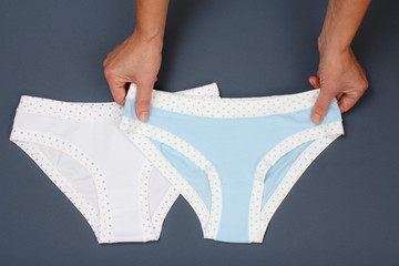 Women's hands with beautiful panties on gray background.