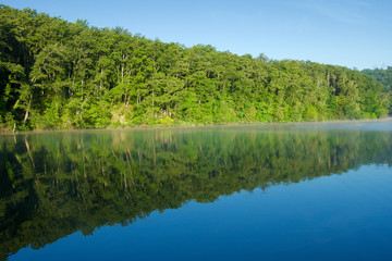 Nature landscape of the Arno River with woods and reflection on the water
