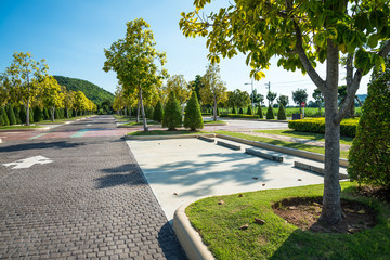 Empty space in city park outdoor concrete parking lot area with blue sky in summer season. Green nature gardening in car parking lot. Friendly environmental and transportation concept.