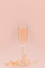 A glass of champagne with bubbles. Christmas balls and a golden lights on light abstract background.