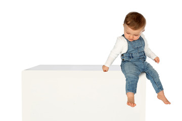 Kleines Kind sitzt auf einem weissen Kasten