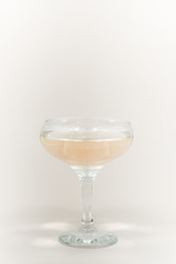 A glass of champagne with bubbles. Christmas balls and a golden lights on light abstract background.