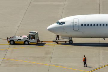 Modern twin engine civil airplane pushing back at international airport