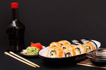 Uramaki California. Sushi rolls, bottle and bowl with soy sauce.