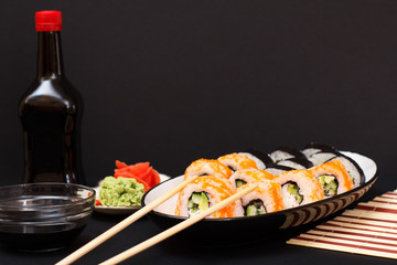 Uramaki California. Sushi rolls, bottle and bowl with soy sauce.