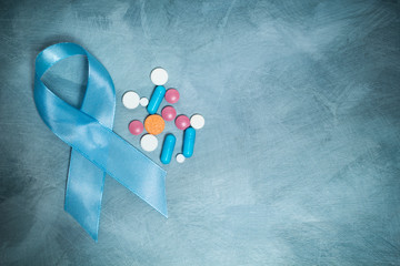 Blue ribbon and pills, a symbol of prostate cancer. Copy space. 