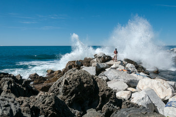 Person standing on rocks with waves crashing