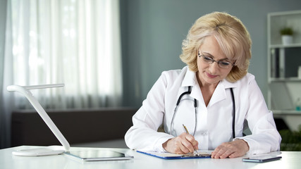 Lady doctor filling in health insurance form before proceeding to treat patient