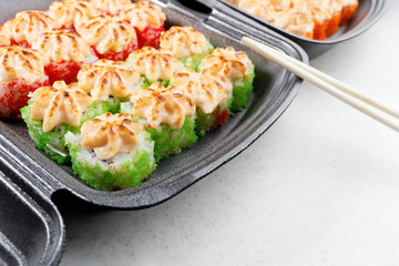 Sushi in plastic packaging. Baked sushi and chopsticks.