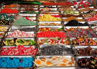 Large shelf full of gummy candy trays of different flavors and colors in a sweets store