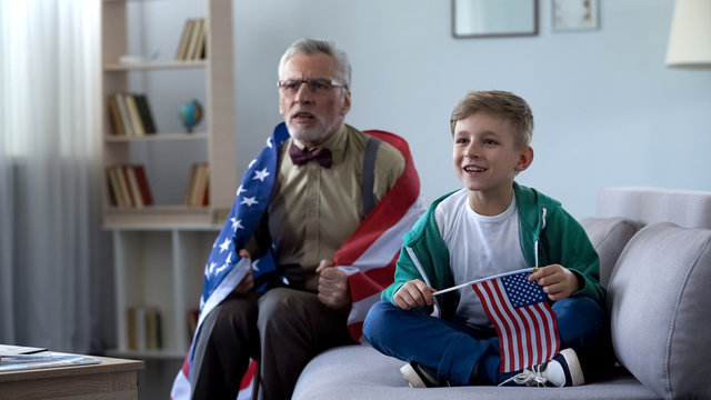 Grandpa Wrapped In American Flag Watching Sport With Boy, Worrying About Game