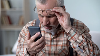 Bewildered old man looking at cellphone, new technology complicated for elderly